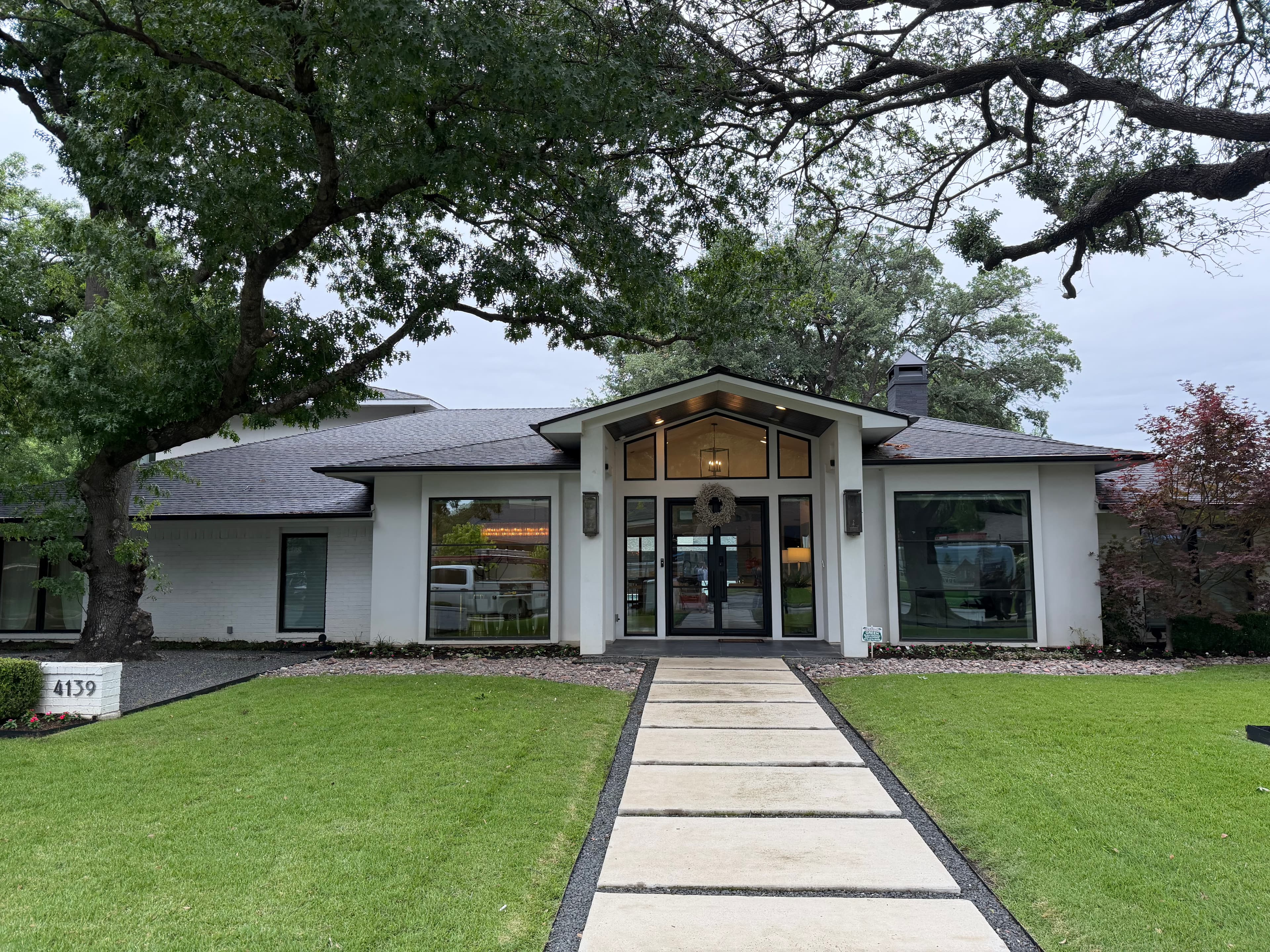 Front elevation of the home with mature oak trees and walkway approach
